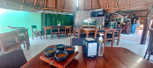 Open-air dining room with thatched palapa ceiling at Maggi's
