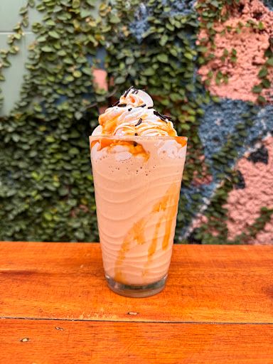 Caramel frappuccino against a green ivy wall at Maggi's